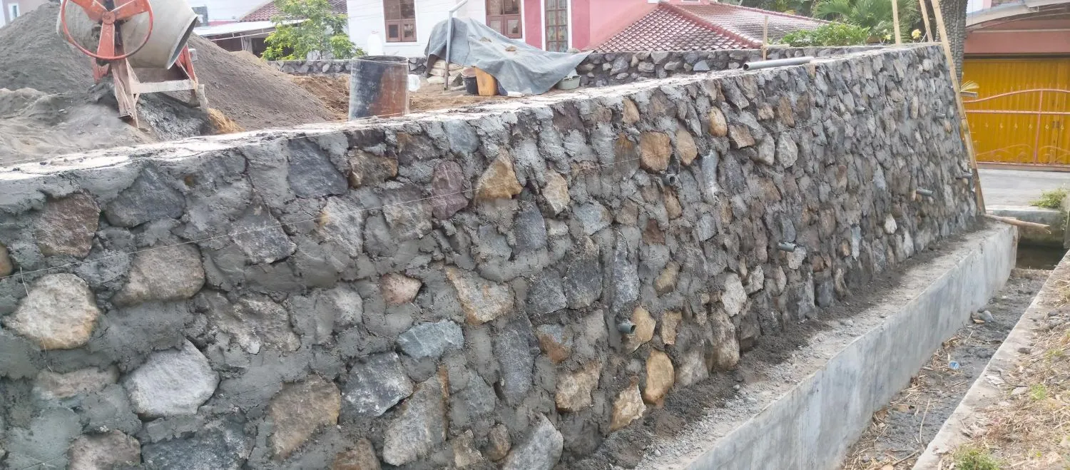 A stone wall is being built in front of a house.