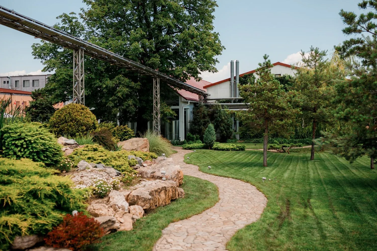 A path going through a lush green park with a building in the background.
