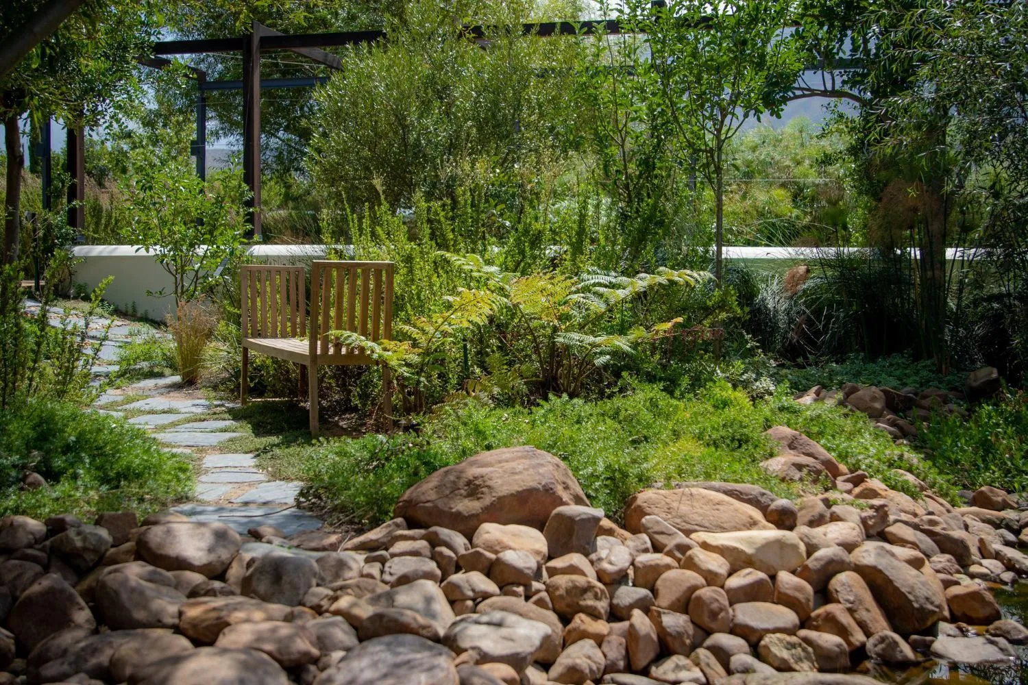 A wooden bench is sitting in the middle of a rocky garden.