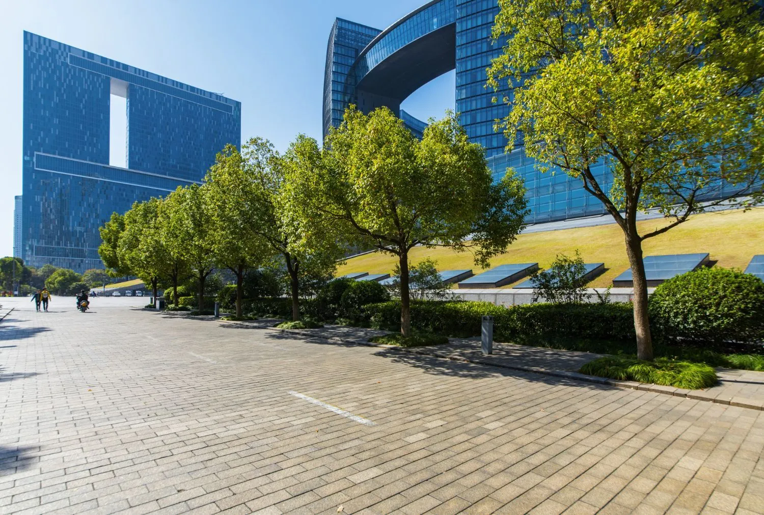 A parking lot with trees and a large building in the background.