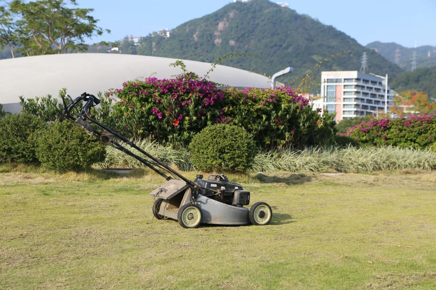A lawn mower is sitting on top of a lush green field.
